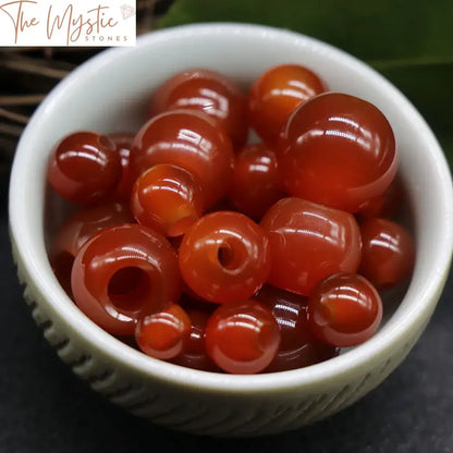 A close-up image of 10 natural red agate stone beads, each with a large hole.