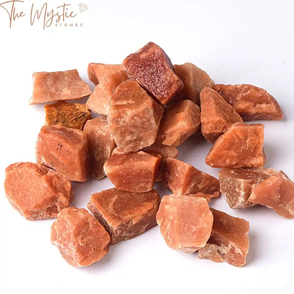 A collection of rough, natural red aventurine crystals scattered across a plain surface.