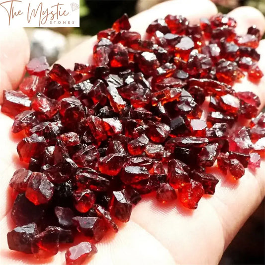 A collection of small, smooth, and polished red garnet stones displayed on a white background.