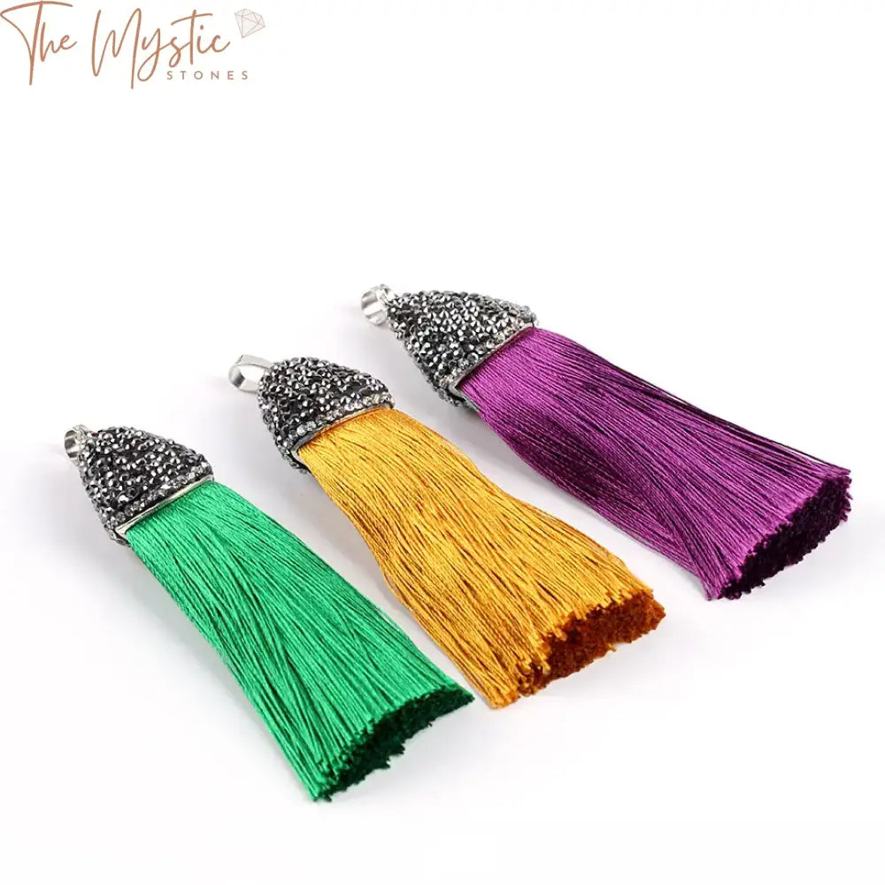 A set of vibrant red tassel charms displayed on a sleek black silk satin background.