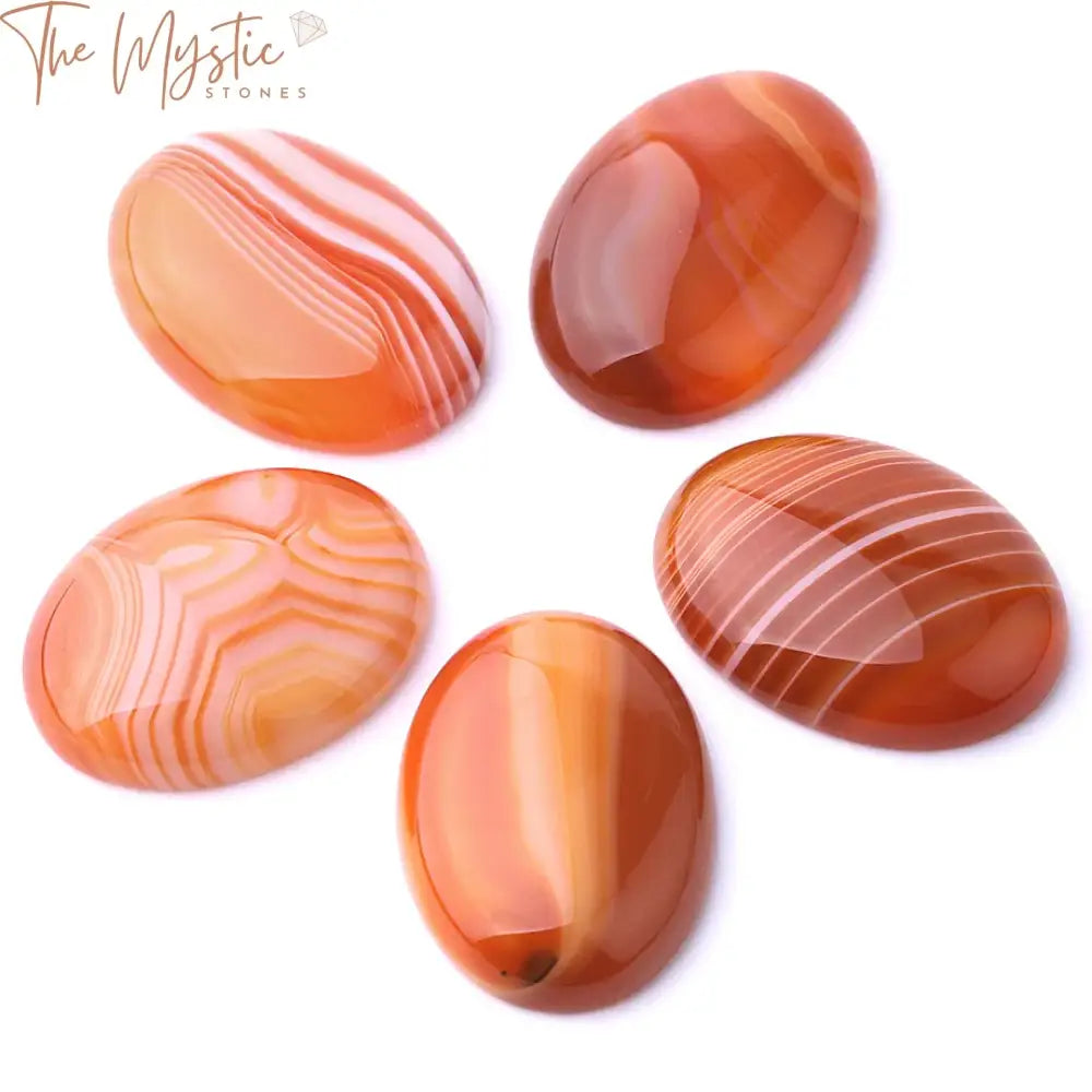 A collection of smooth, oval-shaped cabochons made from red striped agates, featuring distinct layers of red and orange hues.