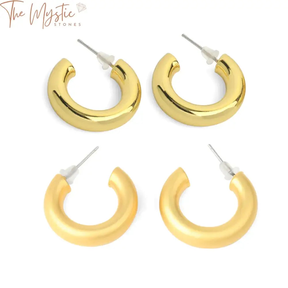 Pair of gold-colored hoop earrings shaped like half moons, featuring a small metal circle resembling the letter C.