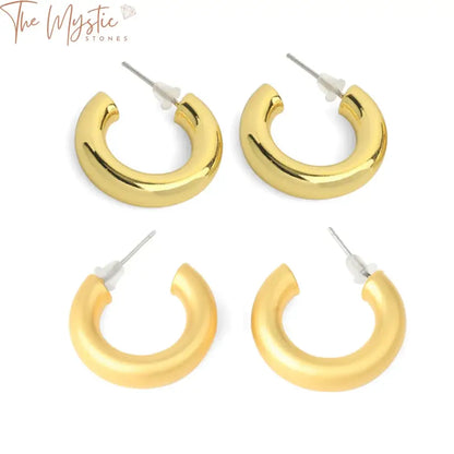 Pair of gold-colored hoop earrings shaped like half moons, featuring a small metal circle resembling the letter C.