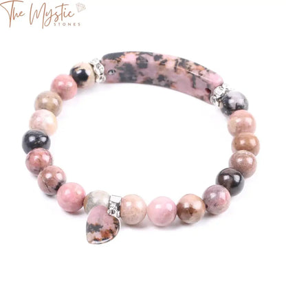 A bracelet made of round rhodonite beads in shades of pink and black, with a central heart-shaped rhodonite stone.