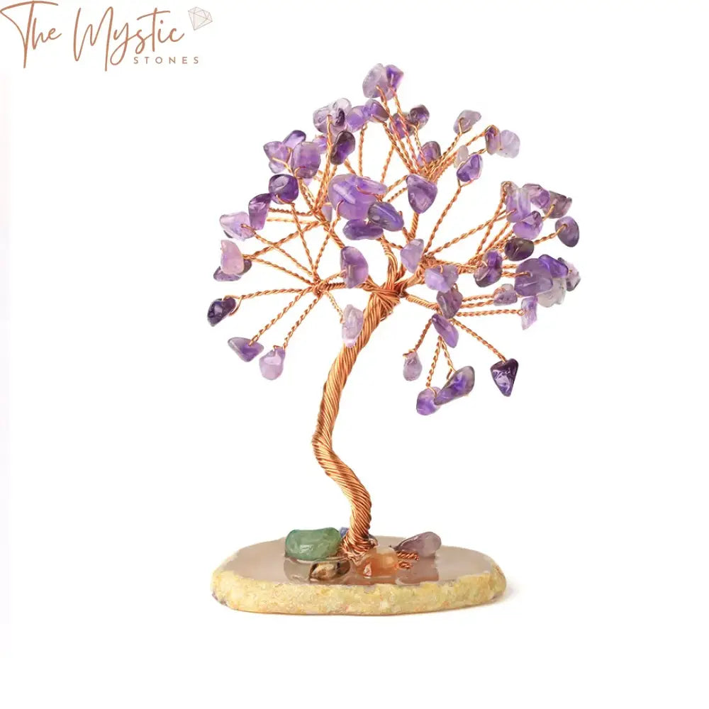 A handmade tree sculpture features natural rose quartz crystal chips as leaves, arranged elegantly on copper wire branches.