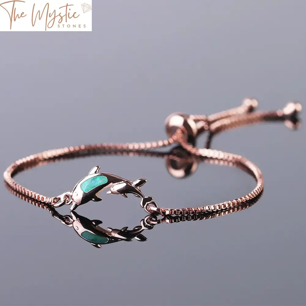 A delicate bracelet featuring two dolphin-shaped charms made from fire opal, set in rose gold.