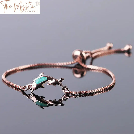 A delicate bracelet featuring two dolphin-shaped charms made from fire opal, set in rose gold.