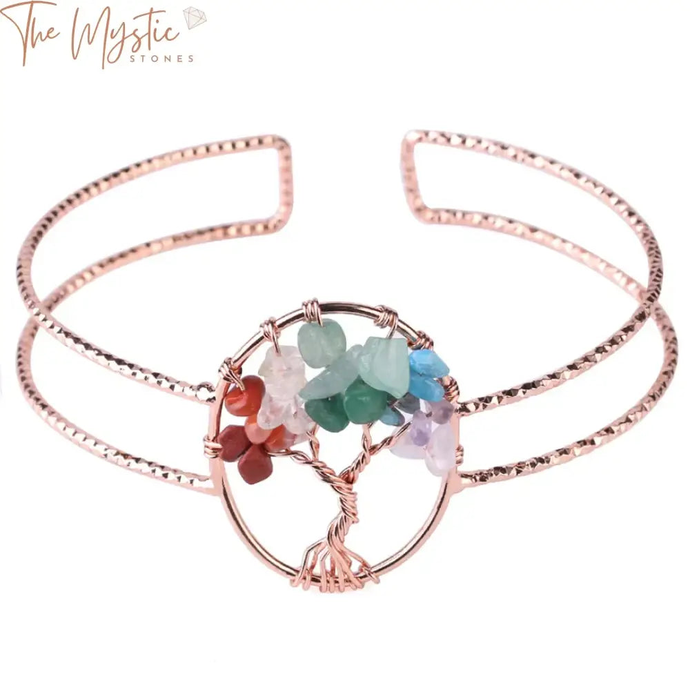 A rose gold-colored wide cuff bracelet featuring an oval Tree of Life charm.