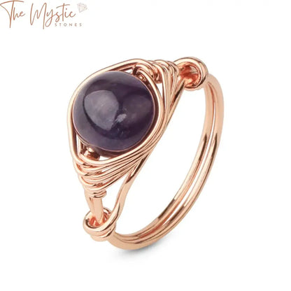 A round natural stone ring featuring a rose gold wire wrap design, showcasing its handmade creativity.