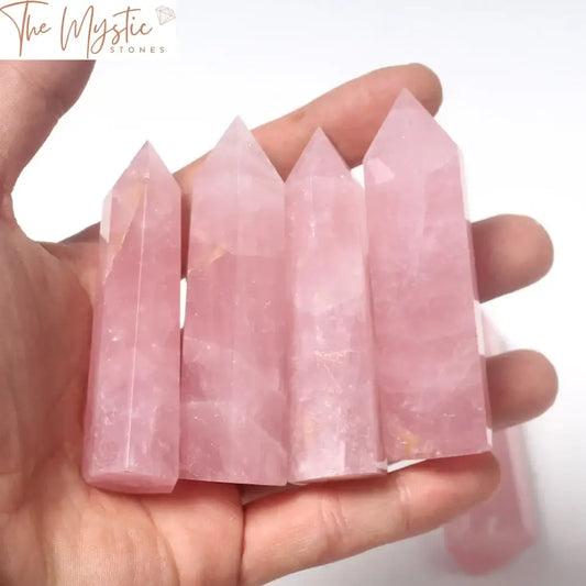 A single piece of natural rose quartz shaped into a hexagonal tower point crystal, exhibiting a soft pink hue.