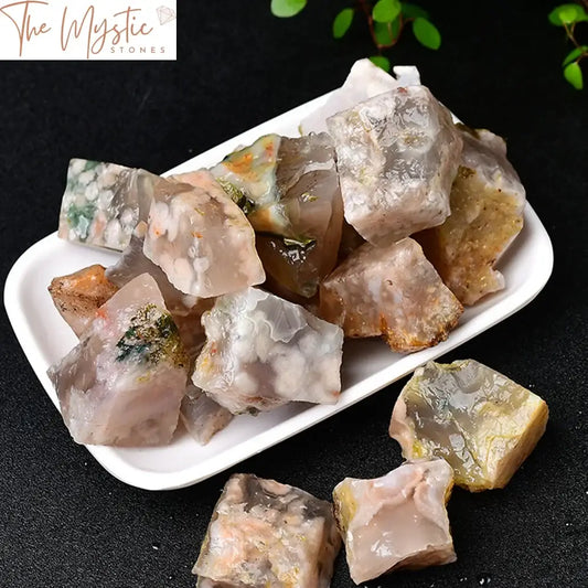 A collection of natural Sakura Agate crystal rough stones displayed on a light surface.