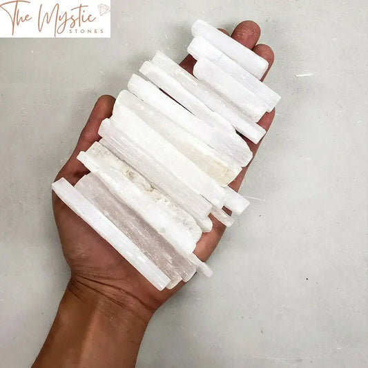 A collection of clear selenite crystal sticks arranged in a neat pile.