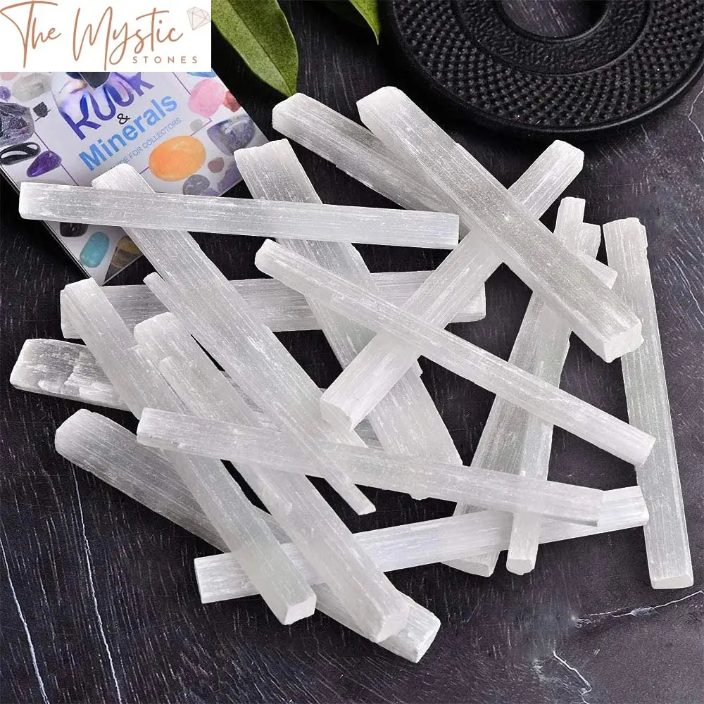 A collection of approximately 20-30 selenite sticks arranged in a neat pile.