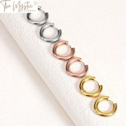 A pair of small, polished stainless steel hoop earrings with a minimal and glossy finish.