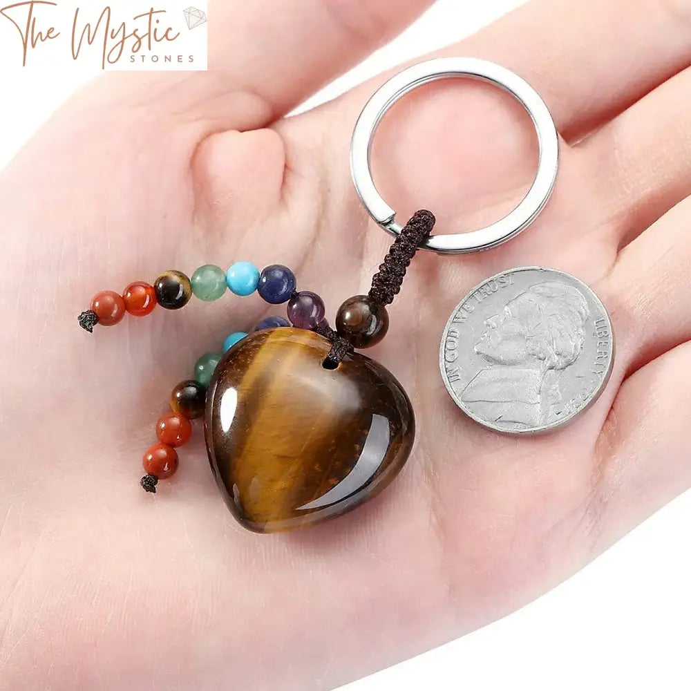 A keychain featuring a natural tiger eye stone carved into a heart shape, accompanied by a tassel.