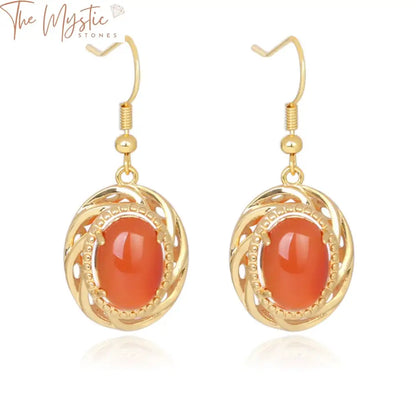 A pair of vintage-style drop earrings featuring oval-shaped red onyx stones set in gold-colored metal.