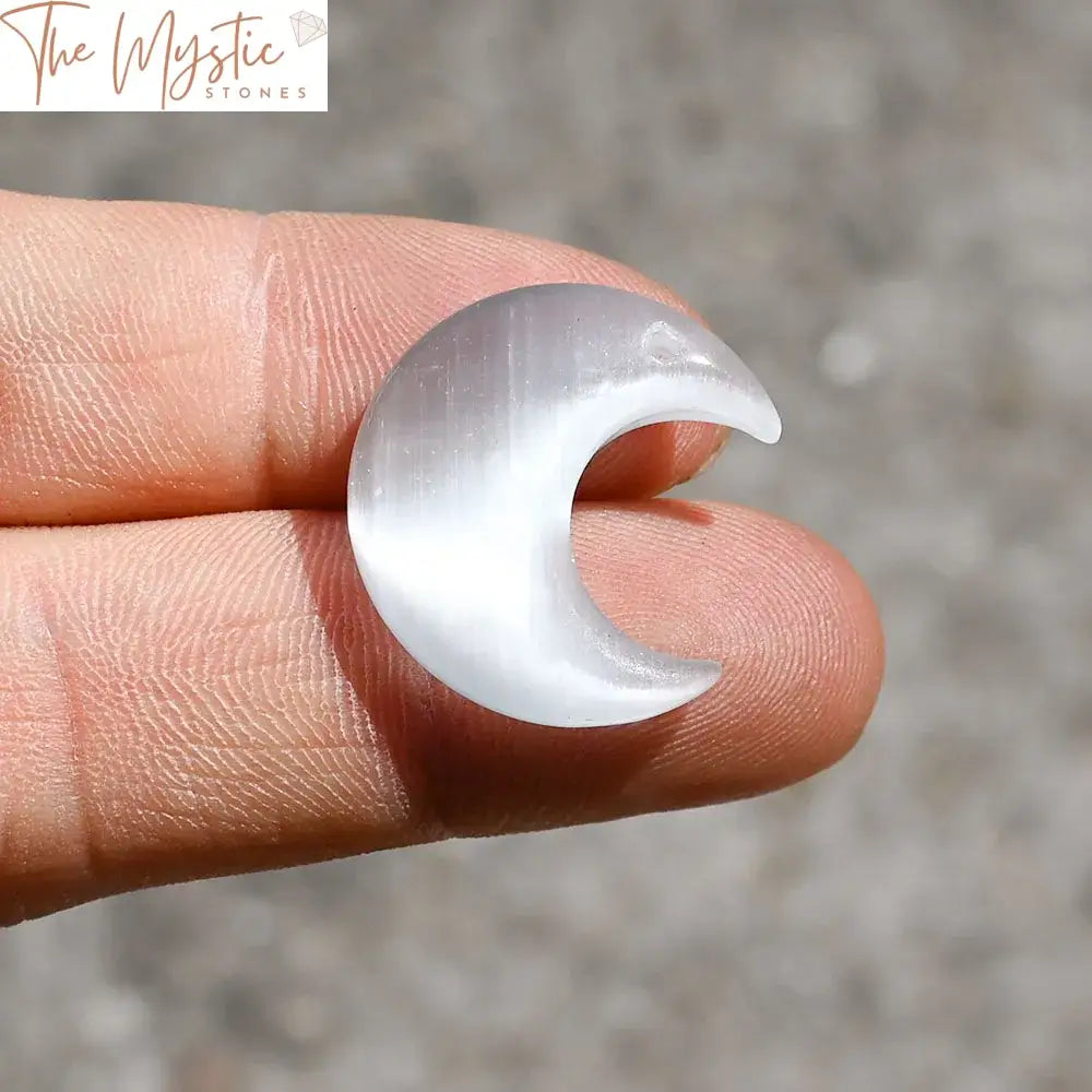 White cat eye stone shaped into a crescent half moon pendant with a small hole at the top for attaching.