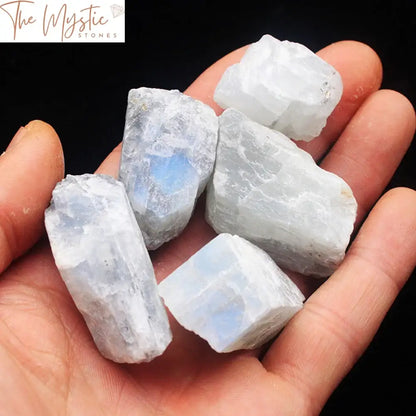 A collection of small, rough white moonstone crystals scattered across a soft surface.