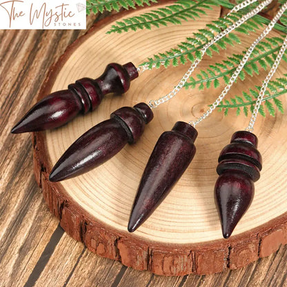 A wooden pendulum intricately carved from dark wood, featuring a pointed tip and smooth, polished finish.