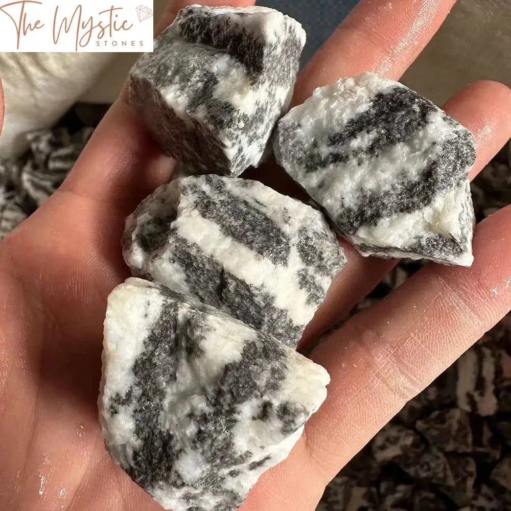 A photograph displays a collection of irregularly shaped black and white Zebra Stone mineral specimens.